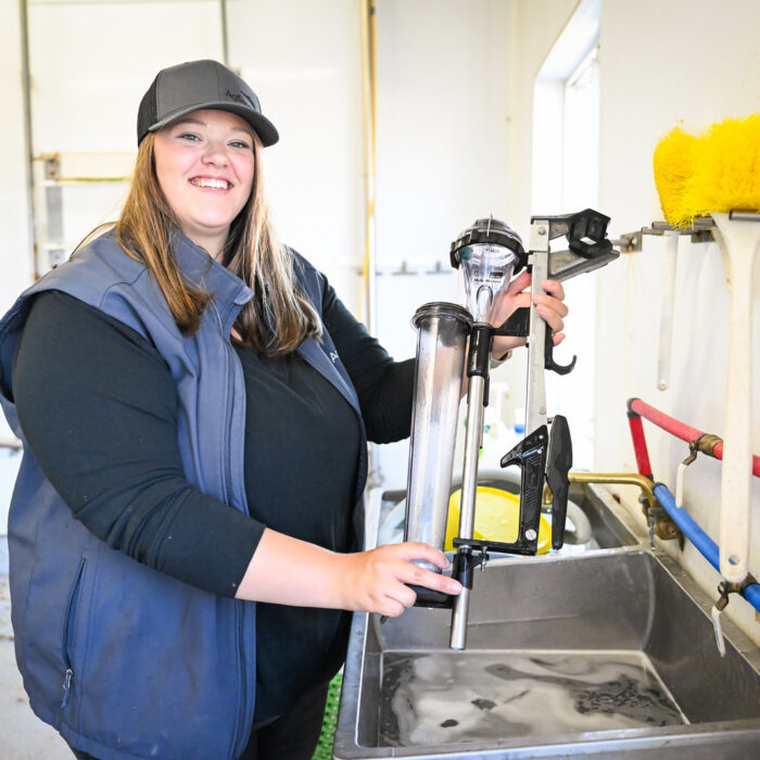 Mikhayla Westra, AgSource Region Manager, holds DHI milk meters in a farm milk house.