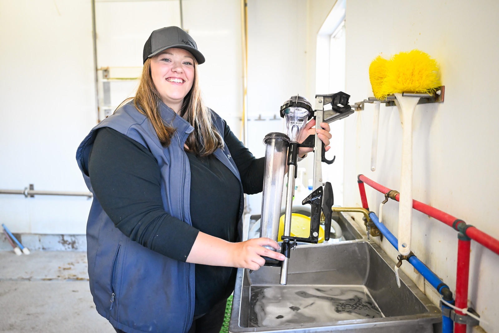Mikhayla Westra, AgSource Region Manager, holds DHI milk meters in a farm milk house.